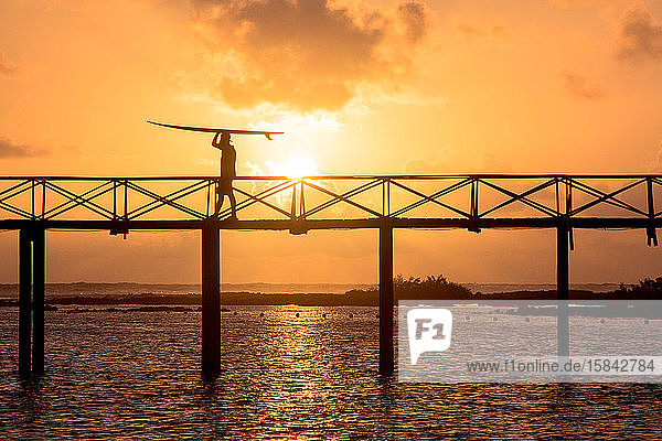 Mann trägt ein Surfbrett auf der berühmten Brücke der Wolke neun auf den Philippinen