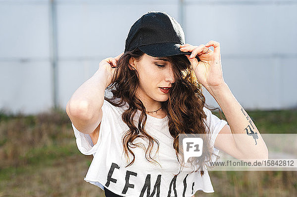 Attractractive millennial woman with long curly hair wearing a cap