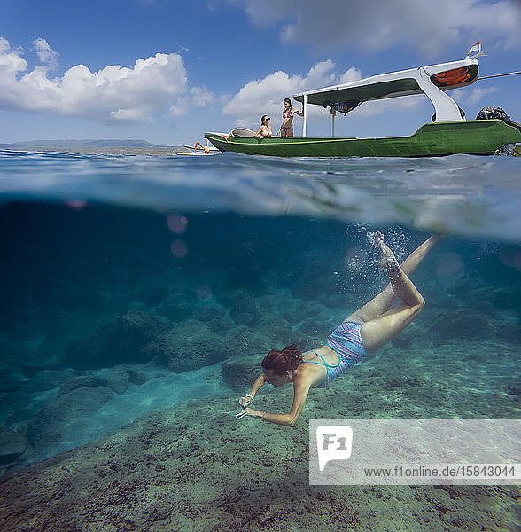 Junge Frau schnorchelt in der Nähe des Bootes im Meer  Unterwassersicht