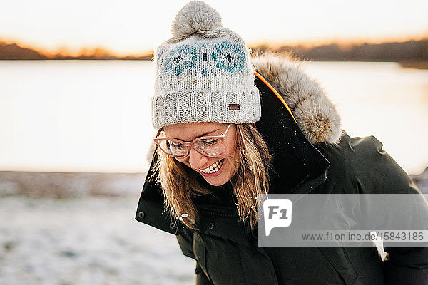 portrait of woman laughing with snow in her hair at sunset