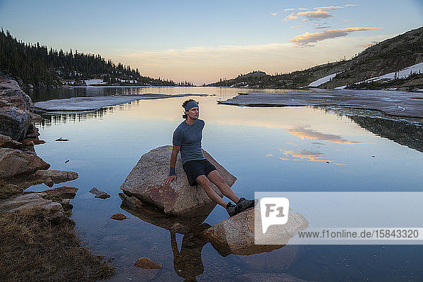 Man on run rests on lake rock in Indian Peaks Wilderness  Colorado