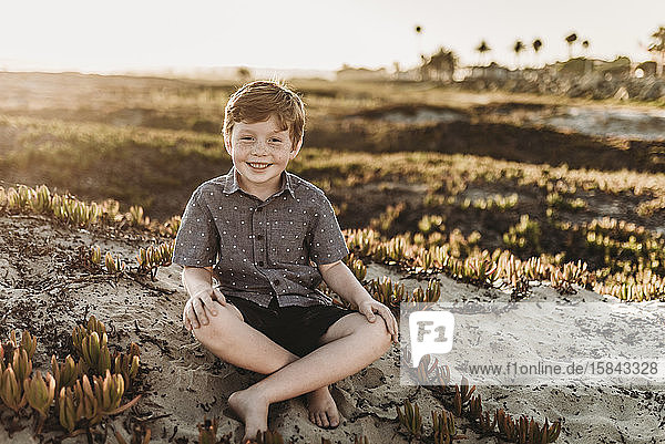 Bildnis eines jungen rothaarigen Jungen mit Sommersprossen sitzend und lächelnd