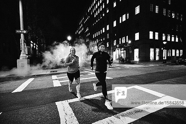 Zwei Frauen rennen nachts in Boston über eine Straße.