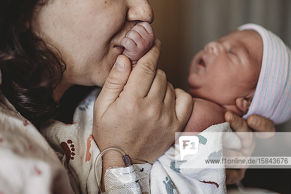 Nahaufnahme einer Mutter im Krankenhaus  die die Hand ihres neugeborenen Sohnes küsst