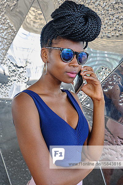 young black woman with very long braids and very attractive and sensual enjoying barcelona in summer and doing model with mobile  glasses and camera  technology concept.