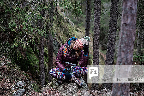 woman sitting on a rock with her head in her hands whilst solo hiking
