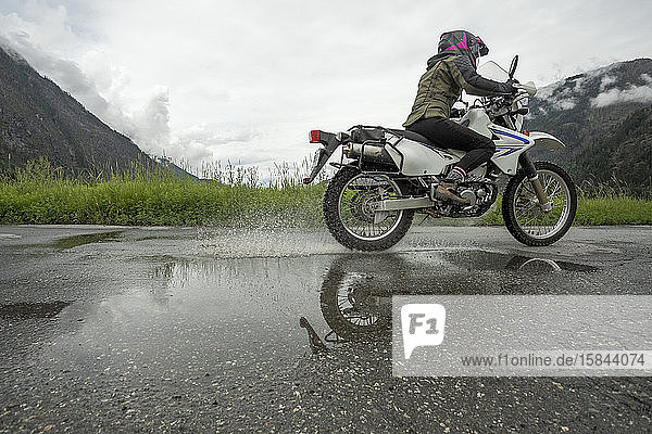 Eine Frau fährt mit ihrem Motorrad an einem bewölkten Sommertag.