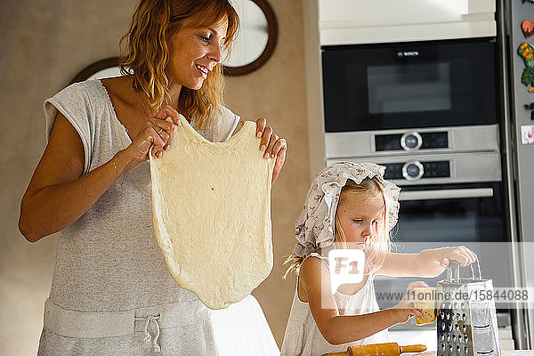 Kleines Mädchen mit Mama beim Pizza-Backen in der Küche