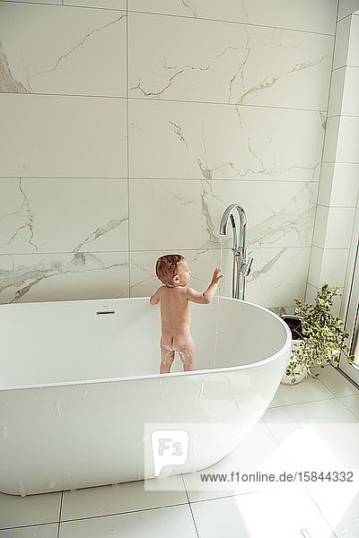 Kleinkind badet nackt in der Badewanne