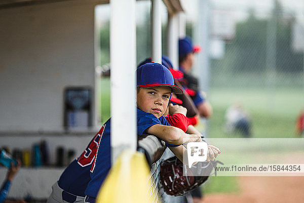 Boy in dugout during little league baseball game
