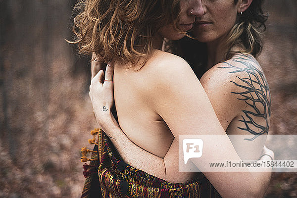 künstlerisches gesichtsloses Porträt eines weiblichen schwulen Paares  das sich im Wald umarmt