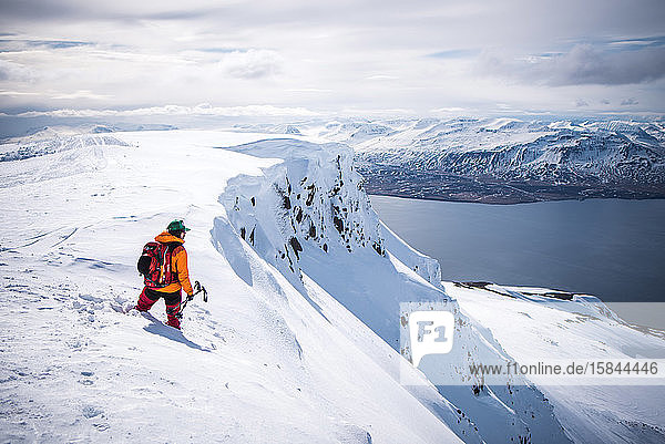 Mann auf Klippe schaut in Island auf den Ozean