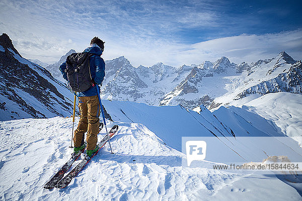 Mann auf Skiern auf dem Grat mit Blick auf den Berg