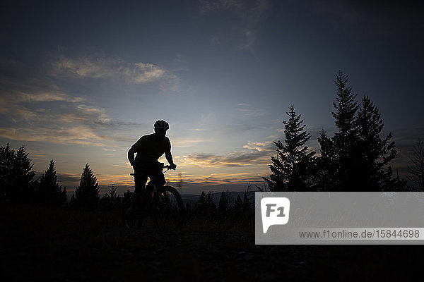 Ein Mountainbiker als Silhouette bei Sonnenuntergang auf dem Gipfel des Blue Mountain.