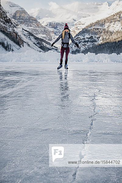 Junge Frau skatet auf gefrorenem See in Richtung Eisriss