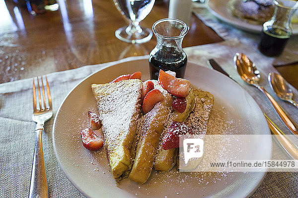 French toast with strawberries  powdered sugar and maple syrup