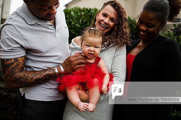 Gemischte Familie lächelt Baby an bedecktem Tag an