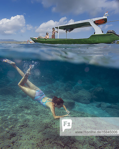 Young woman snorkeling near the boat in ocean  underwater view