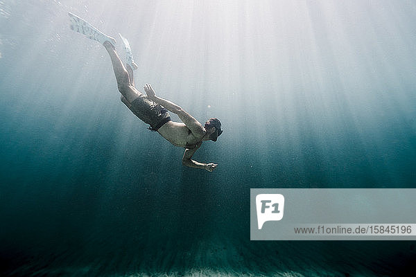 Ein Mann in voller Länge schwimmt unter Wasser im Ozean