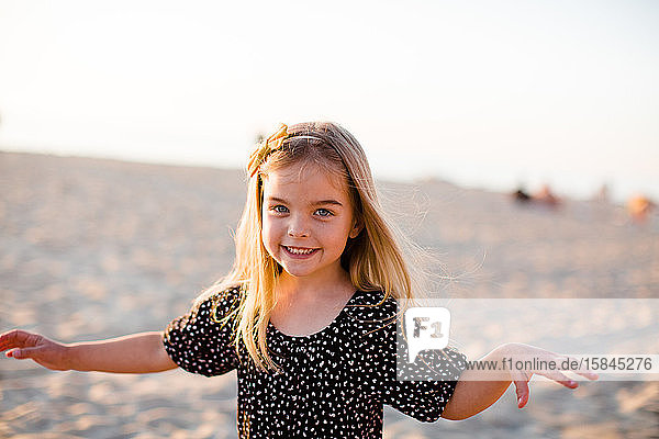 Young Girl Playing on Beach  Smiling at Camera at Sunset