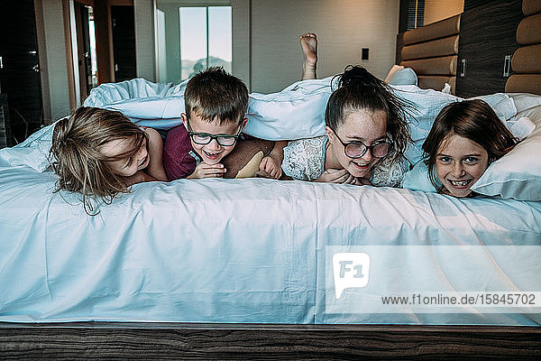 siblings laying on bed facing forward in hotel room
