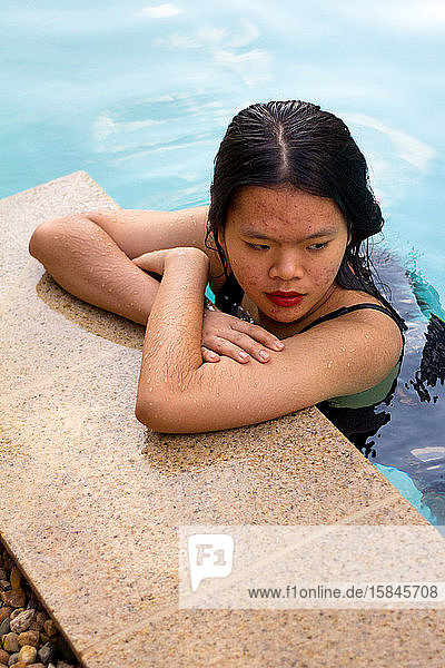 Porträt einer asiatischen Frau  die beim Einsteigen in den Pool in eine Seite schaut