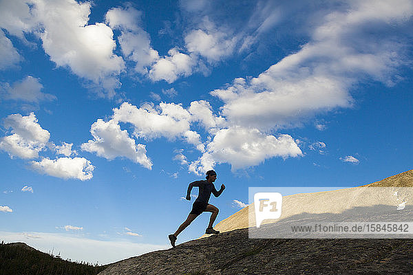 Man runs up rock as silhouette in Indian Peaks Wilderness  Colorado
