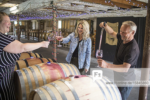 Winzer und Freunde verkosten Wein aus Fässern auf einem lokalen Weingut.