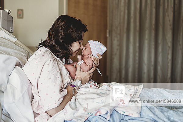 Seitenansicht der Mutter und des neugeborenen Sohnes beim Berühren der Nasen im Krankenhaus