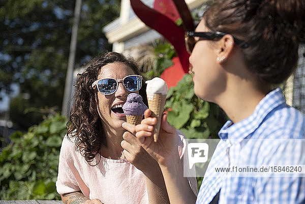 Zwei Frauen essen Eiswaffeln in der Sonne.