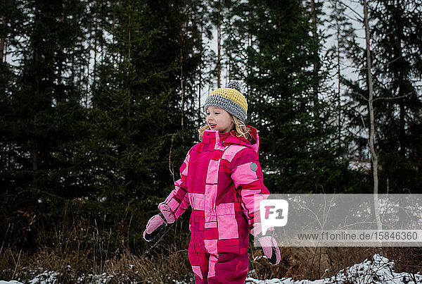 junges Mädchen  das im Winter in einem Schneeanzug durch den Schnee läuft