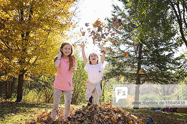 Two Young Girls Playing in Fall Leaves