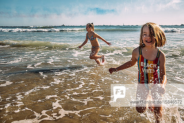 aktionsaufnahme von Mädchen  die am Strand von Huntington im Wasser spielen