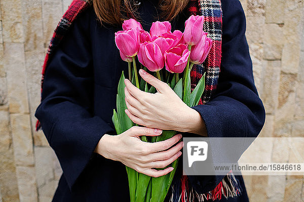 junges französisches tausendjähriges Mädchen in Baskenmütze und Mantel mit Tulpen in den Händen