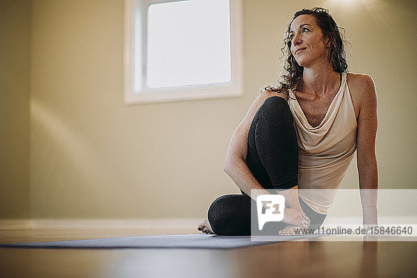 Barfüßige Frau entspannt sich auf Yogamatte in einem Innenstudio