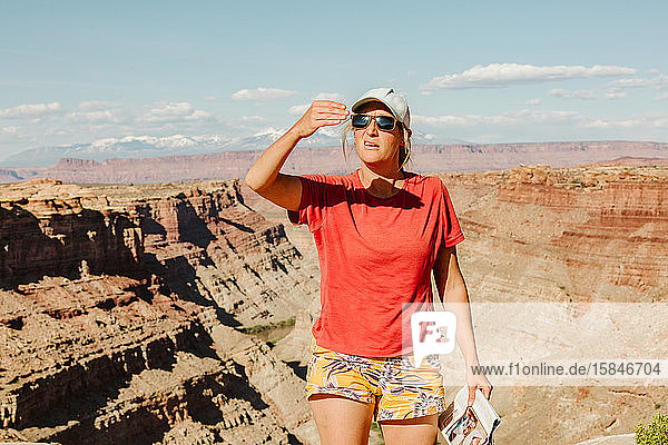 female hiker bocks sun with her hand to measure sunset time in utah
