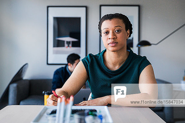 Porträt einer selbstbewussten Geschäftsfrau  die schreibt  während sie im Büro am Tisch sitzt
