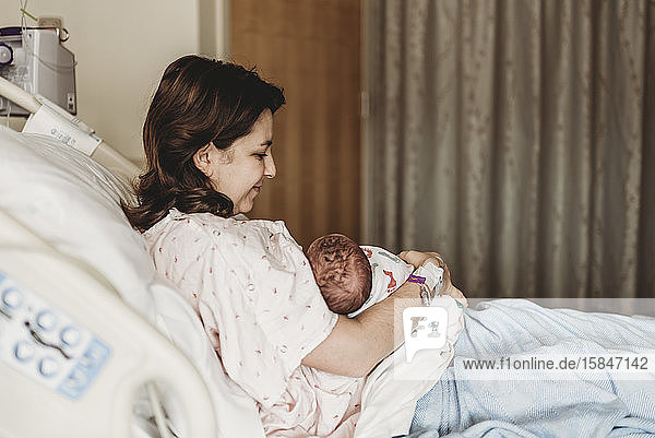 Seitenansicht einer glücklichen Mutter  die ihren neugeborenen Sohn im Krankenhaus hält