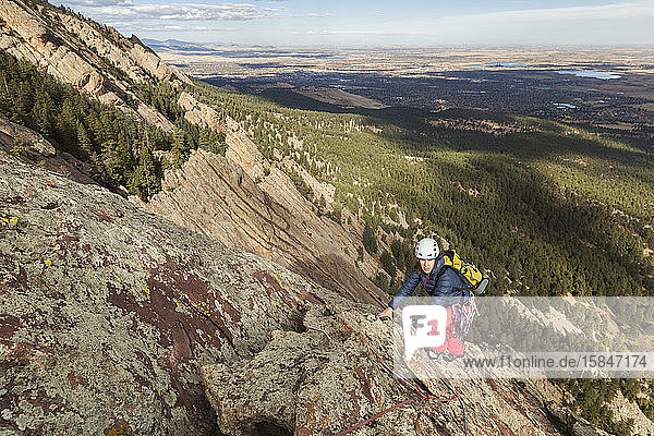 Woman rock climbs The Maiden in Flatirons above Boulder  Colorado