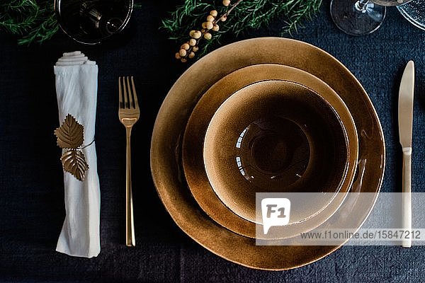 goldene Teller und Schüsseln mit goldenem Besteck auf einem geschmückten Esstisch