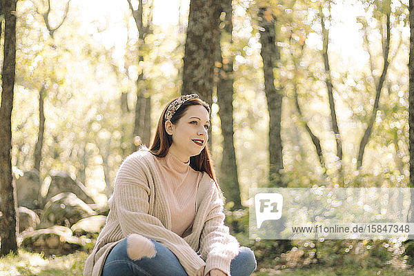 Junge Frau sitzt auf einem Picknicktisch umgeben von einem Wald