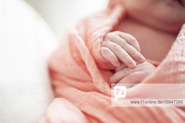 Nahaufnahme der Hände neugeborener Mädchen in rosa Decke gewickelt