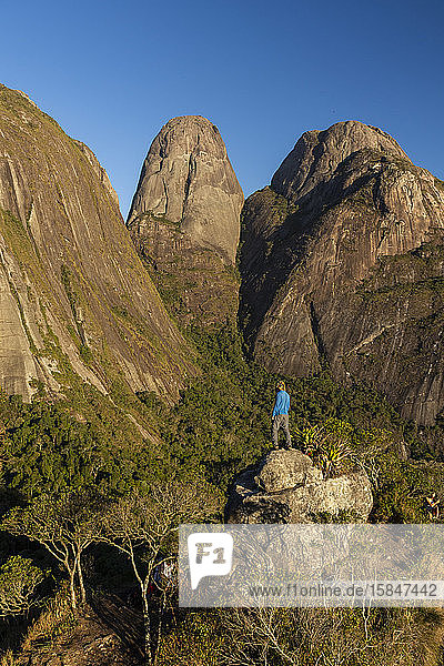 Mann posiert in der Nähe dramatischer felsiger Berggipfel im Regenwald