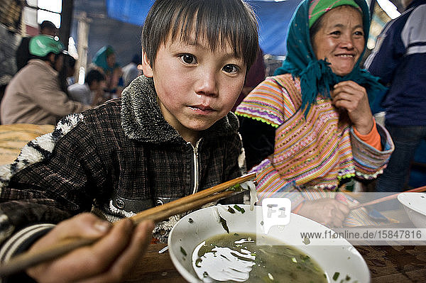 Junger Hmong-Junge genießt eine Schüssel Suppe auf dem traditionellen Markt von Bac Ha