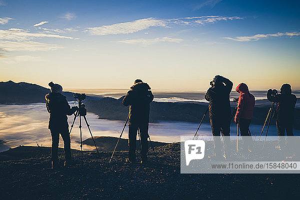 Fotografen bei Sonnenaufgang auf dem Gipfel des Berges