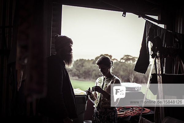 Silhouette einer Frau und eines Mannes vor dem Fenster eines Schuppens auf dem Bauernhof