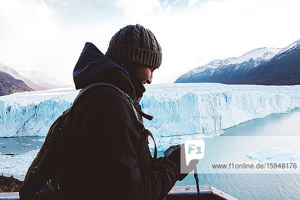 Männlicher Reisender überprüft seine Kamera in Gletschernähe an bewölktem Tag