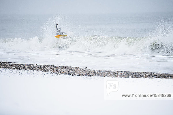 Mann surft im Winterschnee