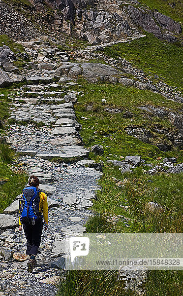 woman with rucksack hiking up rocky path