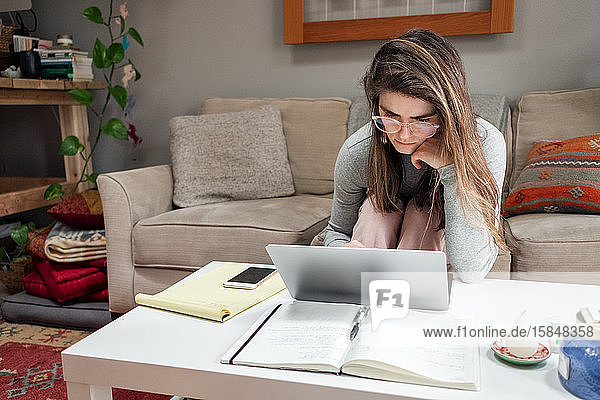 Junge Frau arbeitet während COVID von zu Hause am Laptop